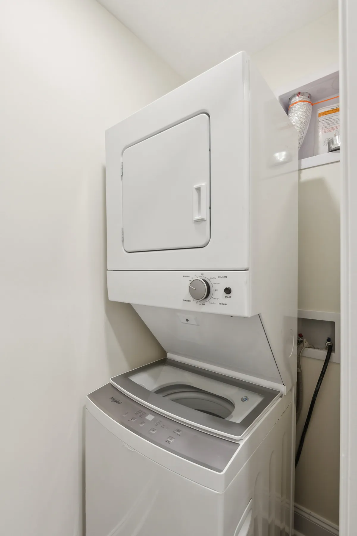 A stacked washer and dryer unit in a clean, organized nook, emphasizing convenience and efficient household management for busy guests.