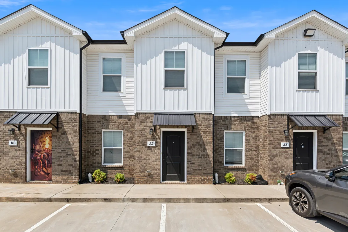 A welcoming exterior view of townhouse front doors with charming decorative touches and landscaping. The scene suggests a community-oriented environment where residents can relax on porches or enjoy the outdoors with neighbors.