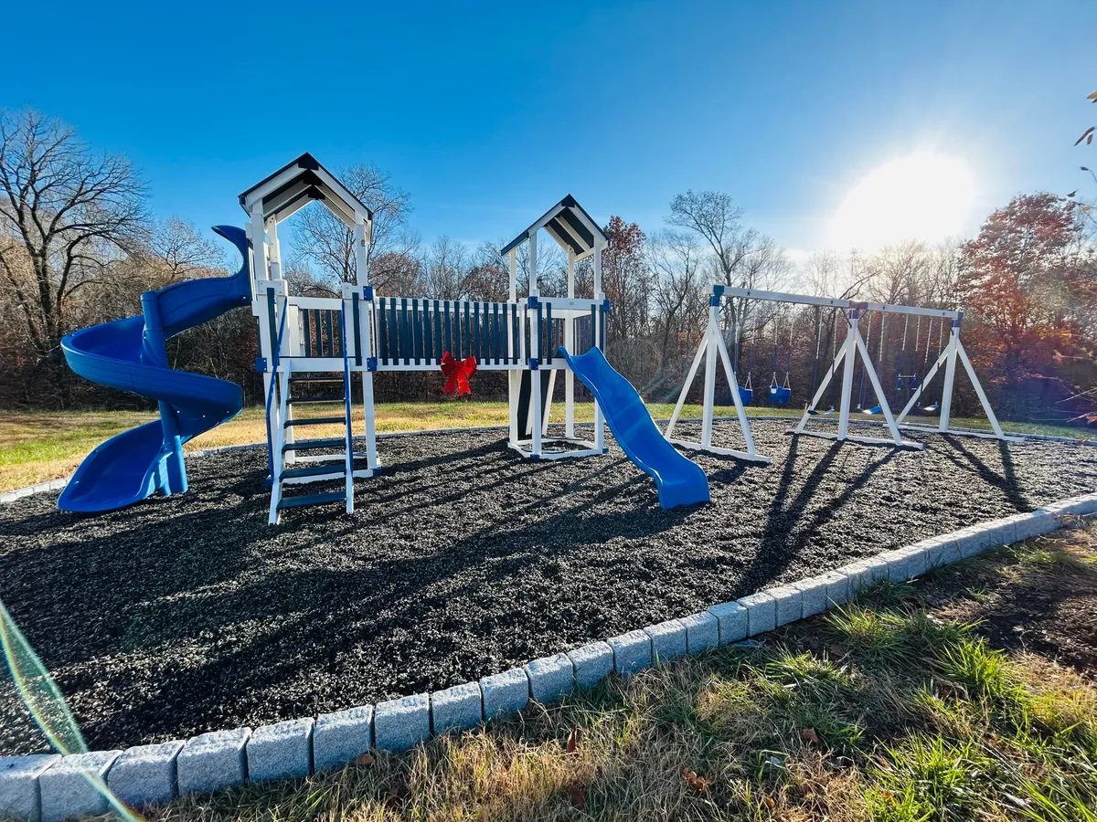A lively playground scene featuring bright playground equipment, including swings and a slide, set in a green outdoor area. Children are seen playing, and the setup is ideal for family gatherings and casual picnics.